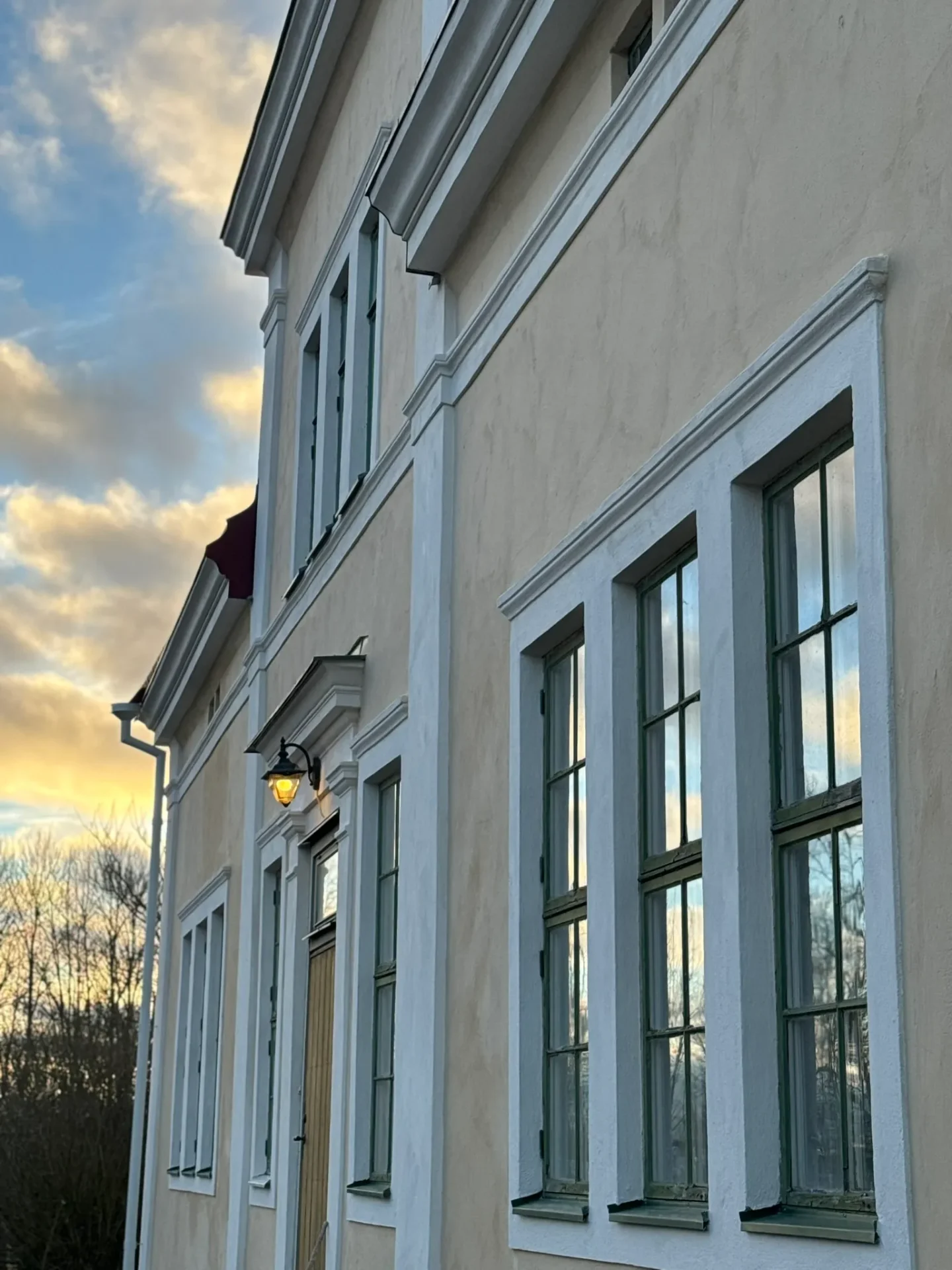 Gul putsad fasad med spröjsade fönster mot kvällshimmel